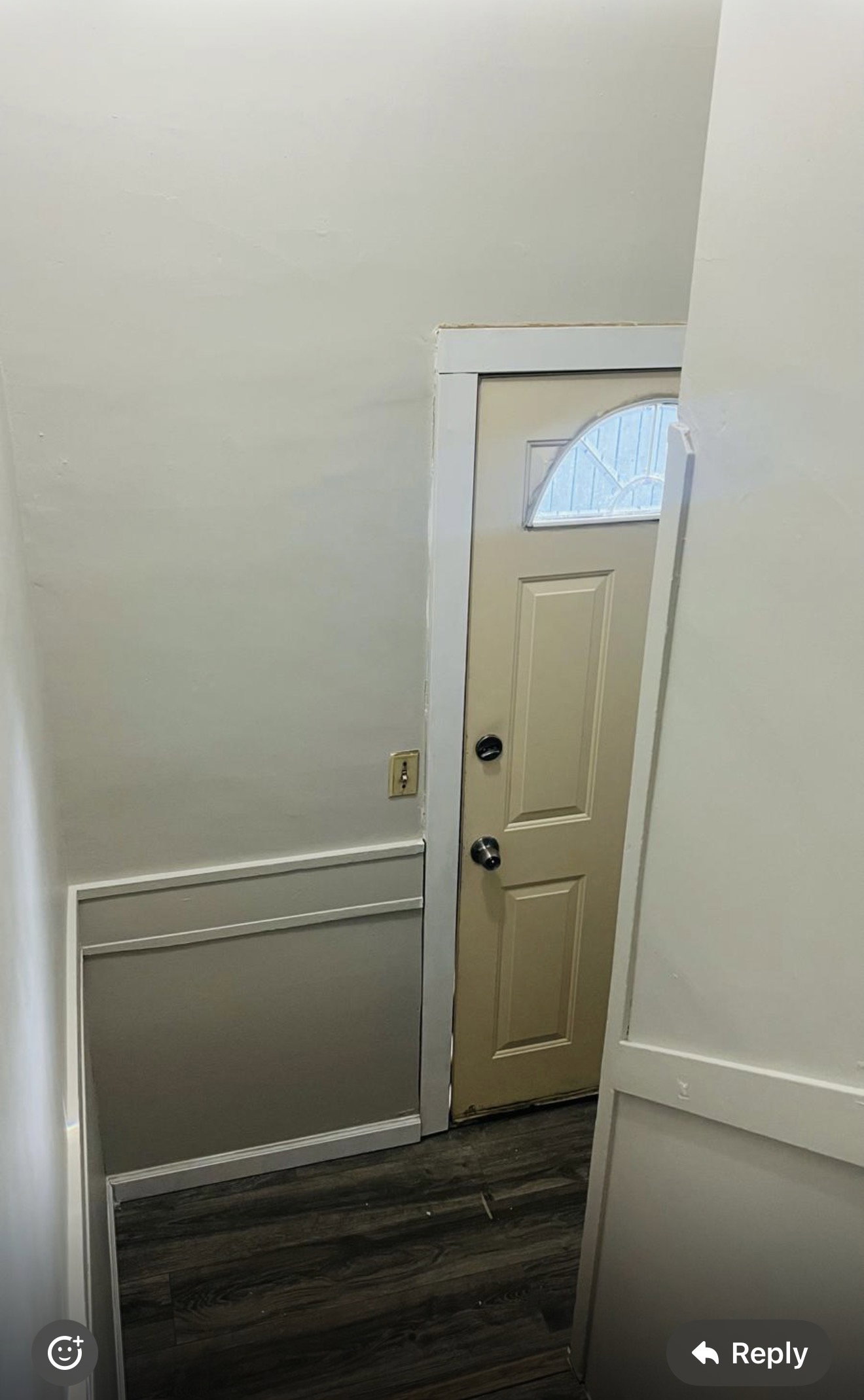 Entryway featuring a paneled door with decorative glass insert, dark wood-finish flooring, and two-tone wall treatment with wainscoting