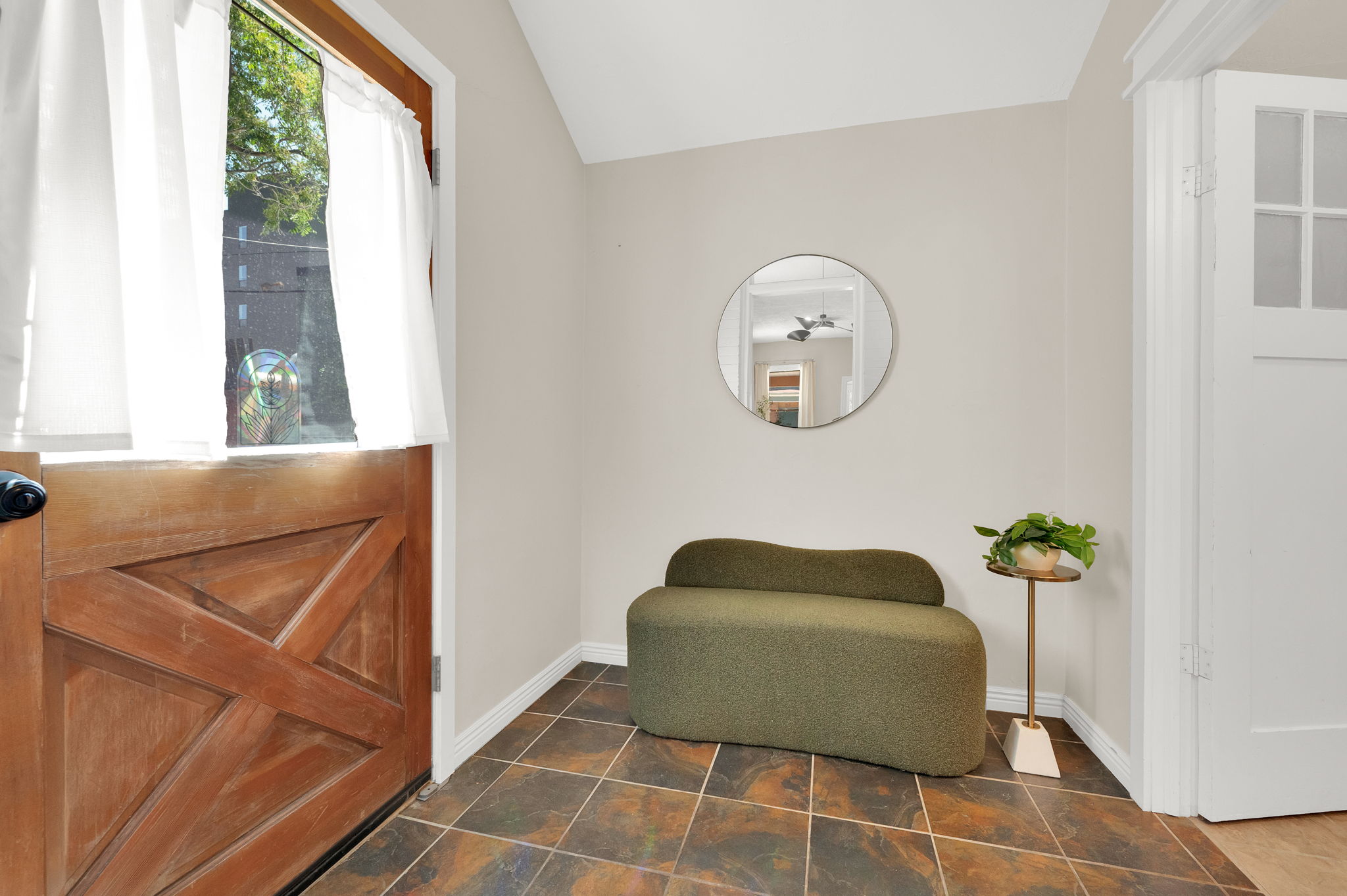 Entryway featuring a wood-panel door with glass upper portion, terracotta-toned tile flooring, light neutral wall paint, and white trim