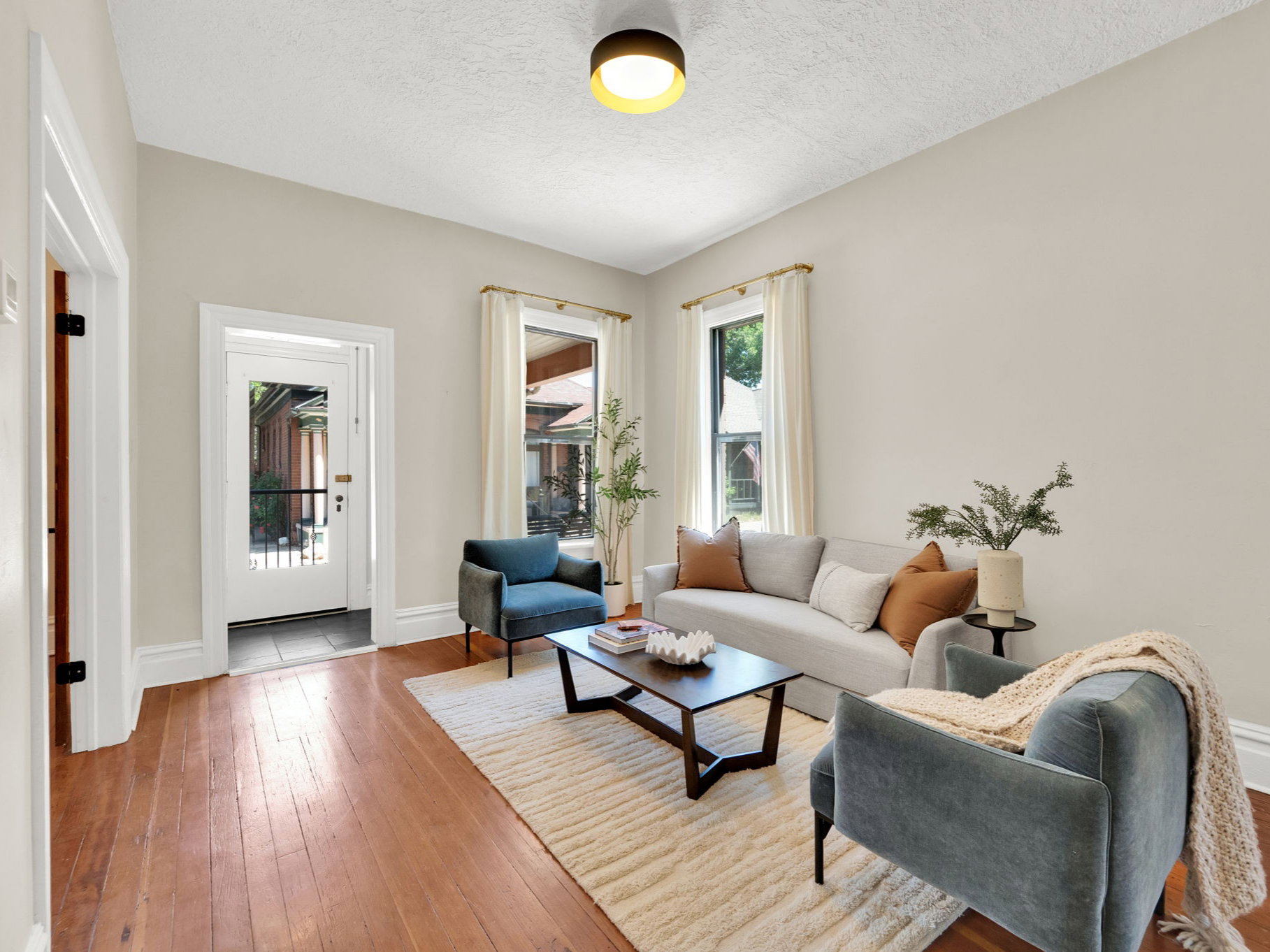 Entry with ornate door and vintage hardware, living area with beautiful hardwood floors.