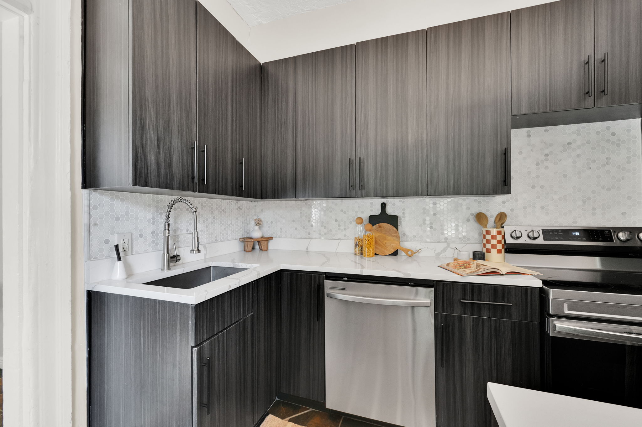 Contemporary kitchen featuring dark wood-finish cabinetry, white countertops, and a mosaic tile backsplash