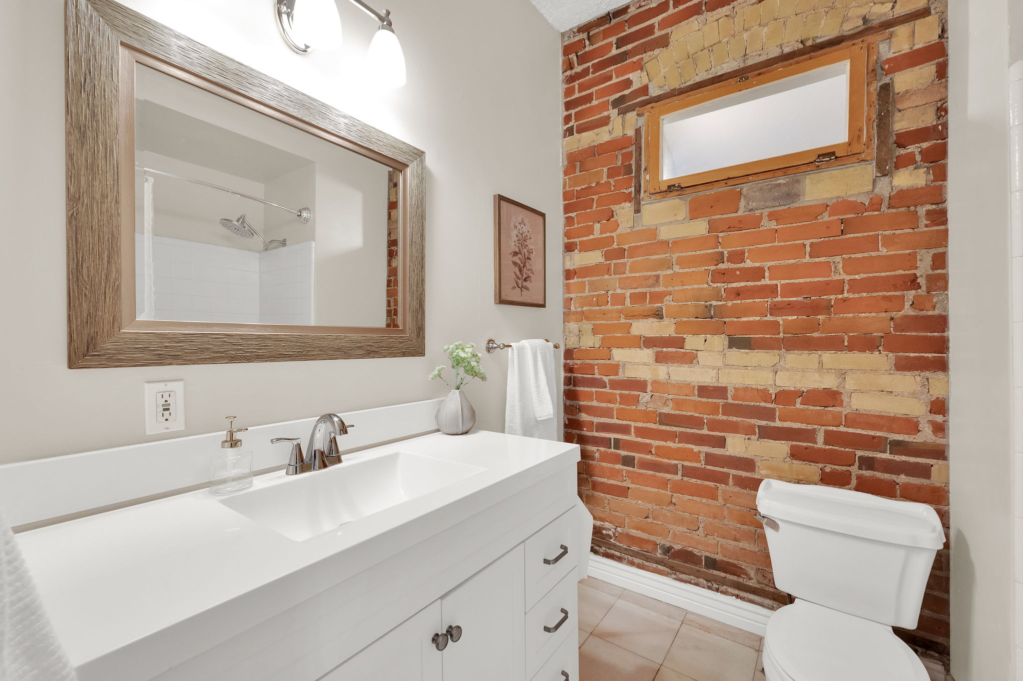 Bathroom featuring a white vanity with integrated sink, brushed nickel faucet, and a large framed mirror
