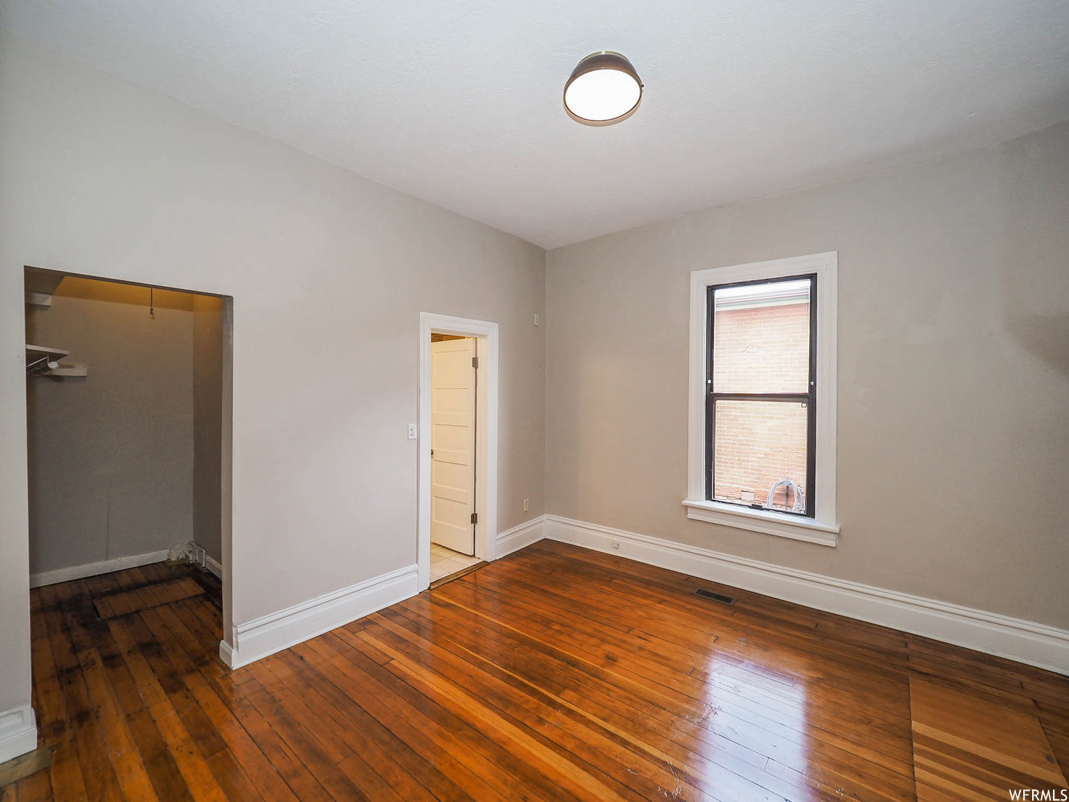 Room featuring wood-finish flooring, light grey walls, and white trim