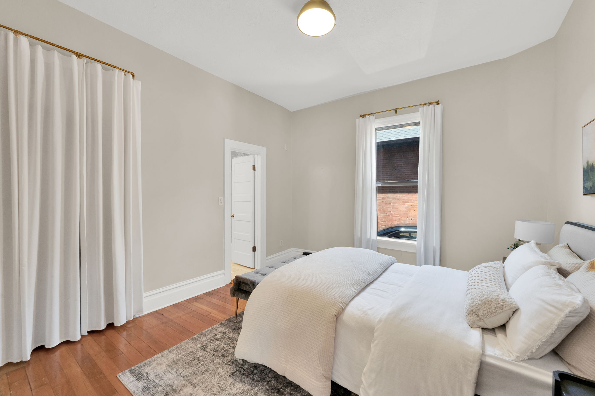 Room with warm-toned wood-finish flooring, light neutral wall paint, and white trim molding