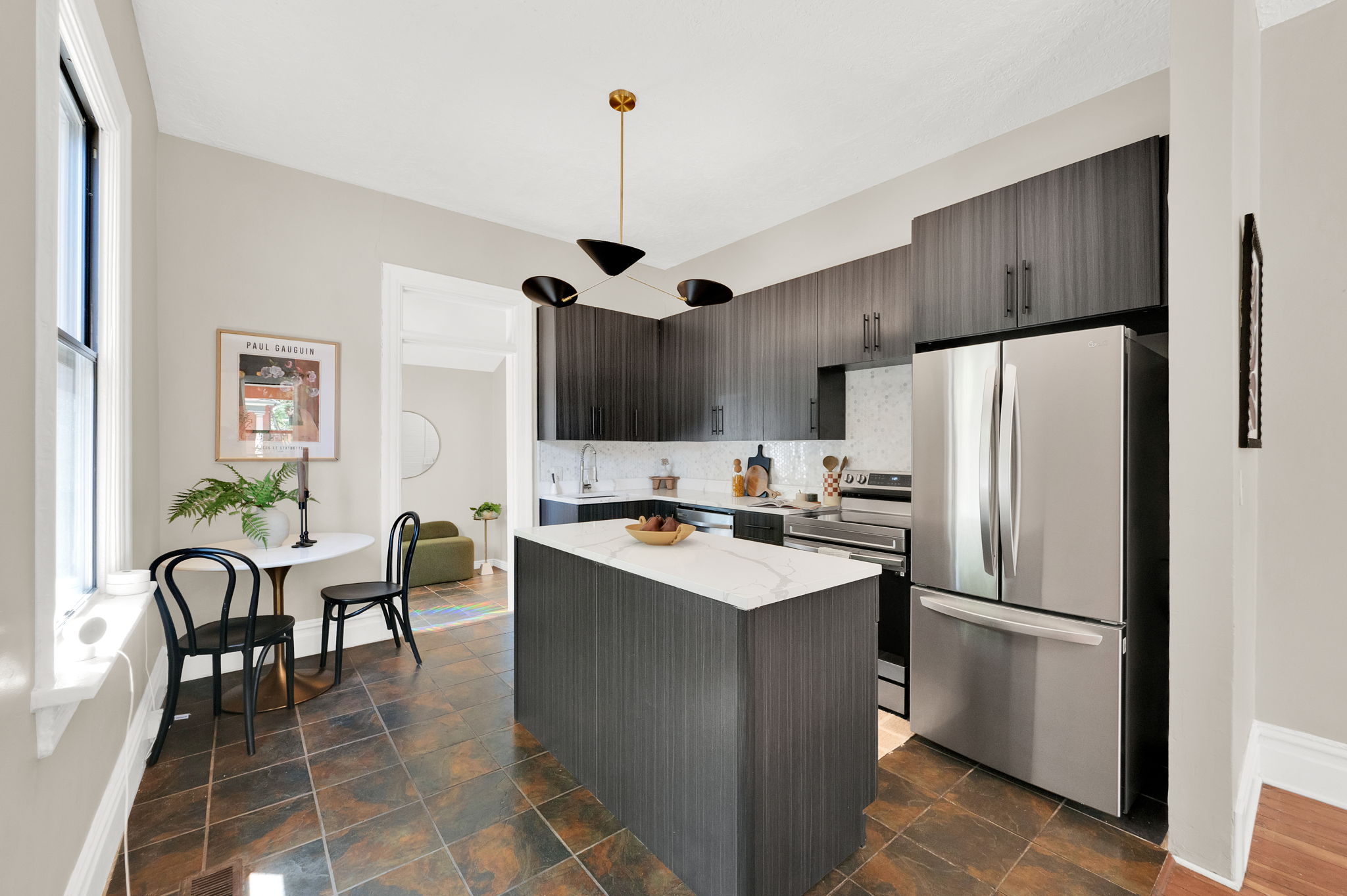 Kitchen featuring dark wood-finish cabinetry, stainless steel appliances, a central island with a white countertop, and tiled flooring