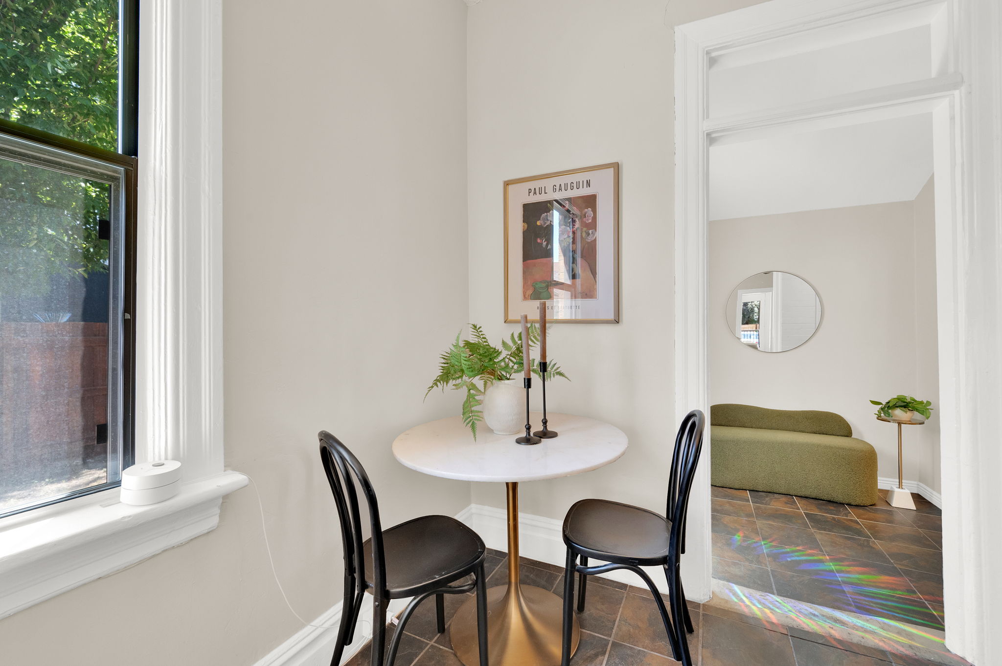 Compact dining area featuring a round white table with a gold pedestal base and dark flooring