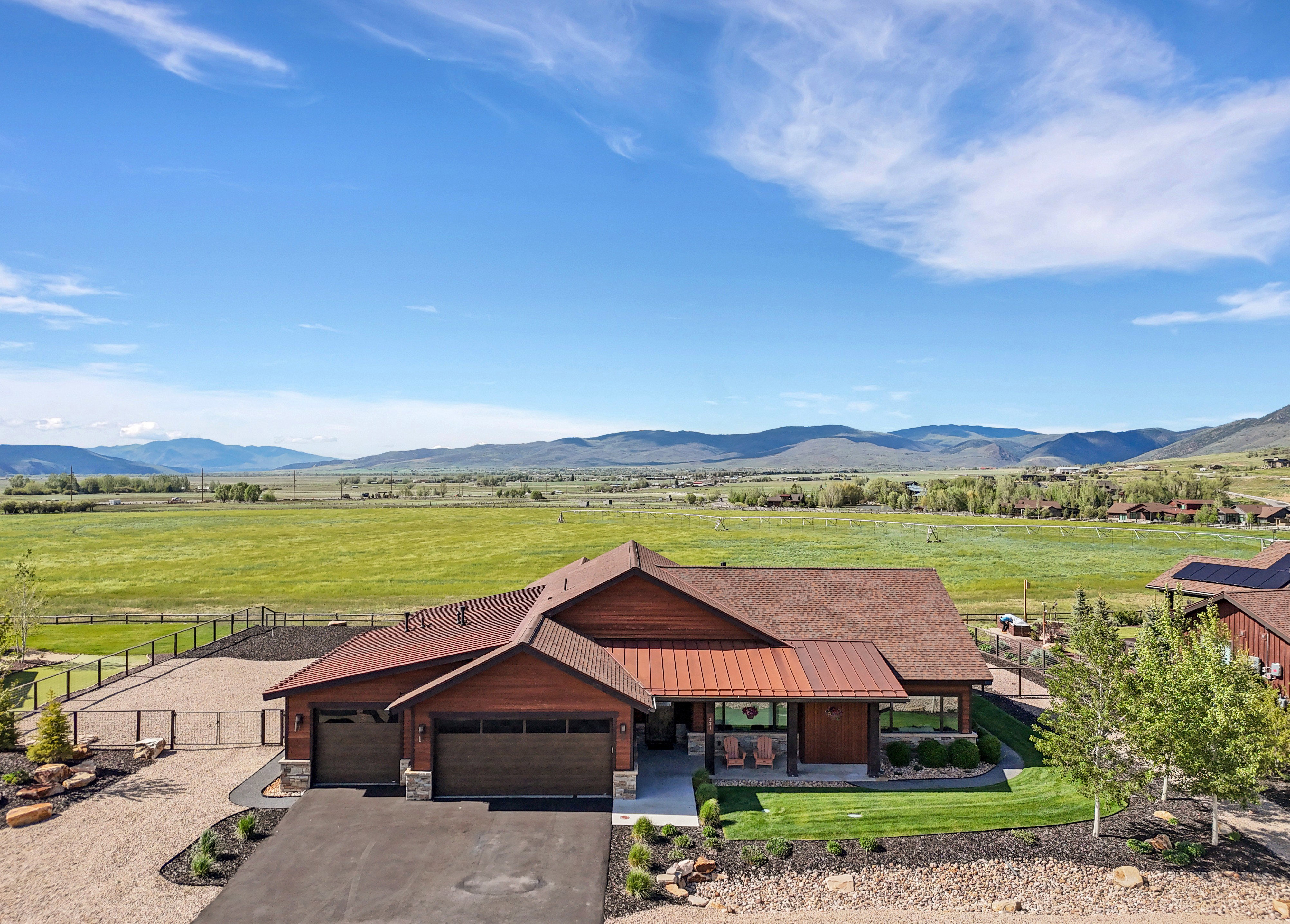 Mountain-backed property featuring a brown-stained wood exterior with stone accents, a multi-gabled roof, and a front porch