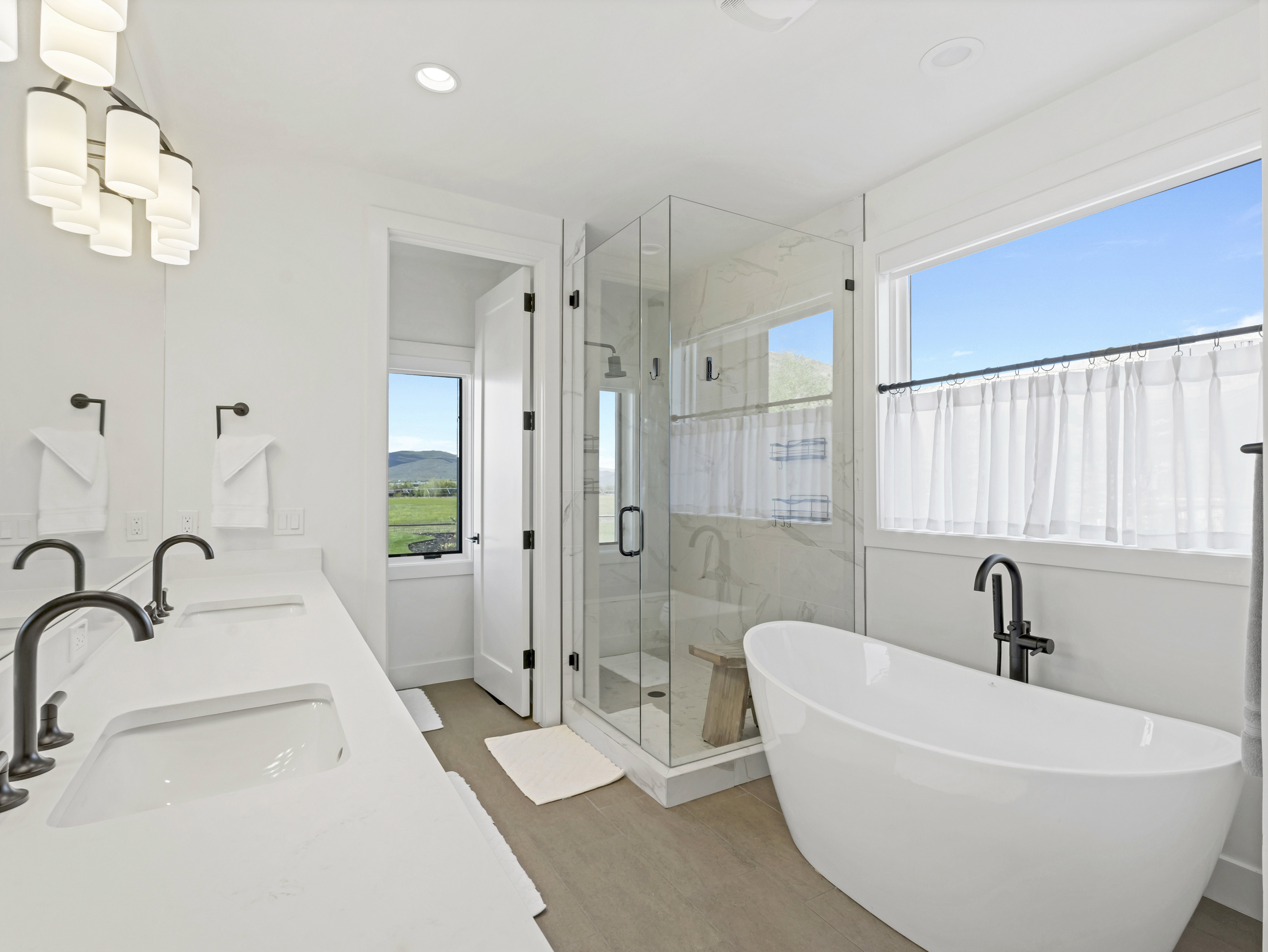 Contemporary bathroom featuring a freestanding soaking tub with floor-mounted fixture, a glass-enclosed shower with tiled walls, and a double vanity with undermount sinks and dark bronze fixtures