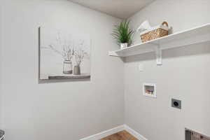 Dedicated laundry area featuring wood-finish flooring, white walls, and built-in white shelving