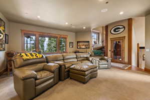 Spacious entertainment room featuring recessed lighting, a large window with natural wood trim, and a built-in wet bar