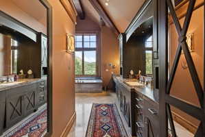 Spacious bathroom featuring twin vanities with stone countertops, integrated sinks, and dark cabinetry