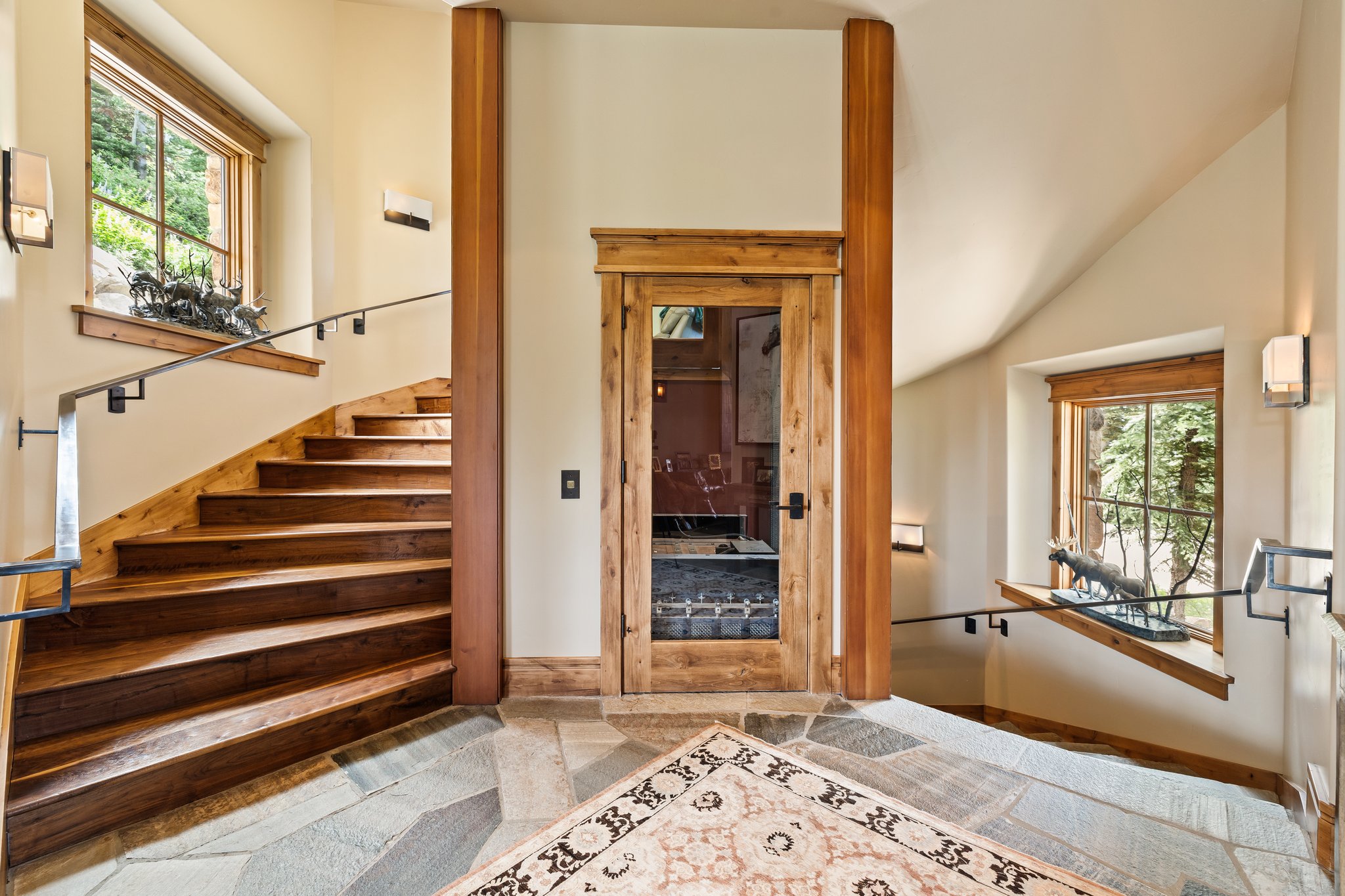 Architectural staircase featuring wood-finish treads and risers, iron railings, and sconce lighting
