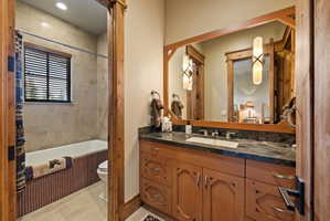Bathroom vanity featuring a dark stone countertop, undermount sink, and custom wood cabinetry
