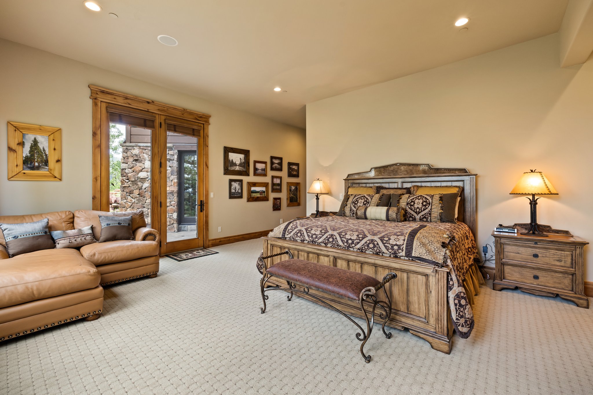 Spacious room featuring patterned carpeting, recessed lighting, and a large wood-framed glass door opening to an exterior stone wall
