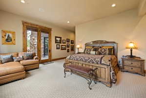 Spacious room featuring patterned carpeting, recessed lighting, and a large wood-framed glass door opening to an exterior stone wall
