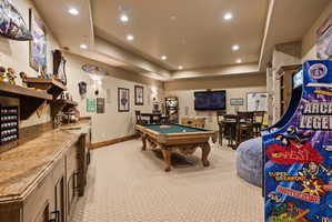 Entertainment space featuring a billiards table, wall-mounted television, recessed lighting, and a built-in wet bar with a stone countertop
