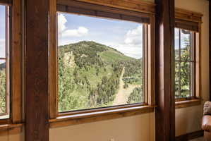 Expansive window framing a mountain landscape with evergreen trees and a ski slope