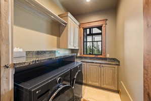 Dedicated laundry area featuring granite countertops, wood-finish cabinetry, built-in shelving, and a grid-paned window with wood trim