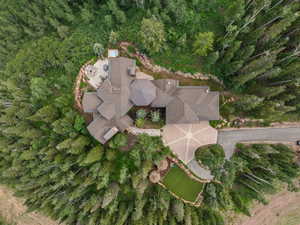 Expansive property featuring a multi-gabled roofline, a large paved driveway with a central design element, a stone patio, and a built-in outdoor spa