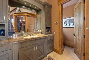 Vanity with a stone countertop, integrated sink, and gray cabinetry featuring cross-brace detailing