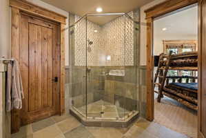 Corner glass shower enclosure with floor-to-ceiling tilework, including small square mosaic tile and large format stone tile