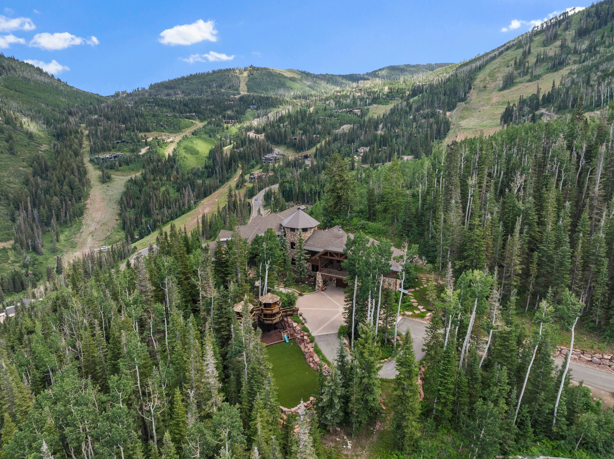 Expansive mountain property featuring a natural wood and stone exterior, surrounded by dense evergreen and aspen trees