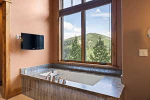Built-in soaking tub with a stone countertop and tile surround