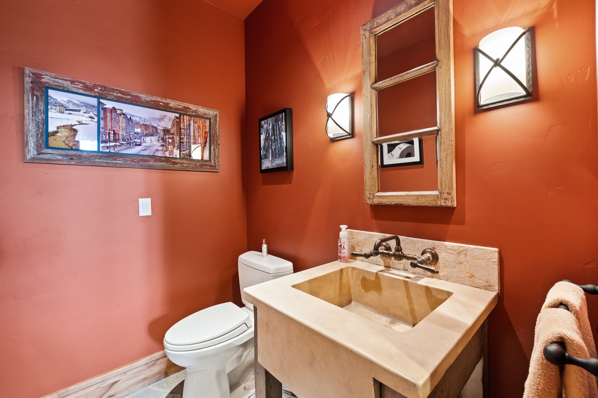 Powder room featuring a custom stone sink, wall-mounted bronze-tone faucet, and a distressed mirror