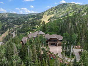 Expansive mountain-style residence featuring multiple gabled roofs, stone and wood siding, and an attached garage with a paved driveway