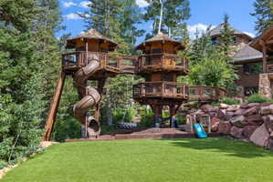 Custom treehouse structure featuring multiple levels, connecting walkways, and a spiral slide