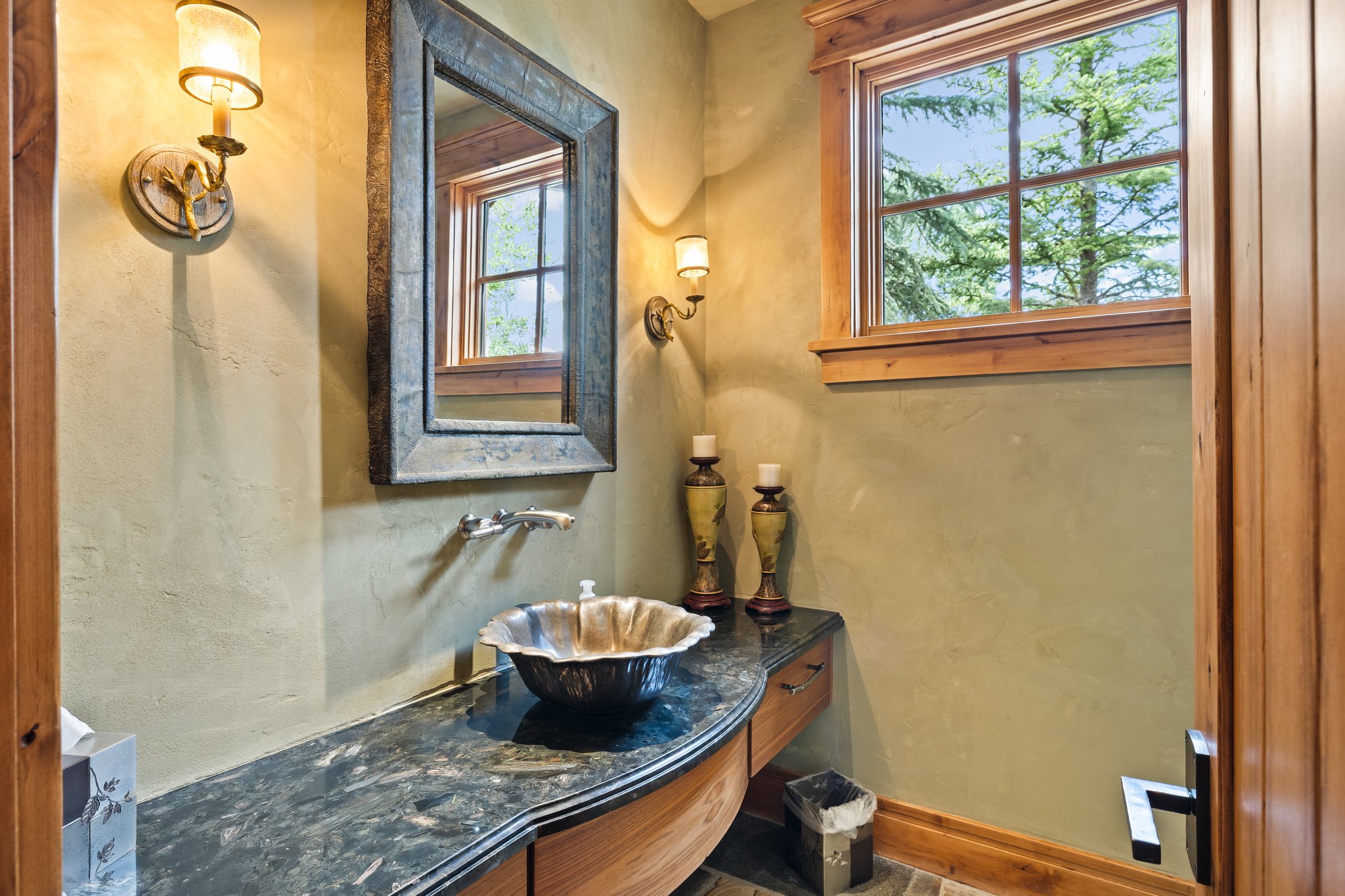 Distinguished vanity with a dark countertop, ornate vessel sink, and wall-mounted faucet