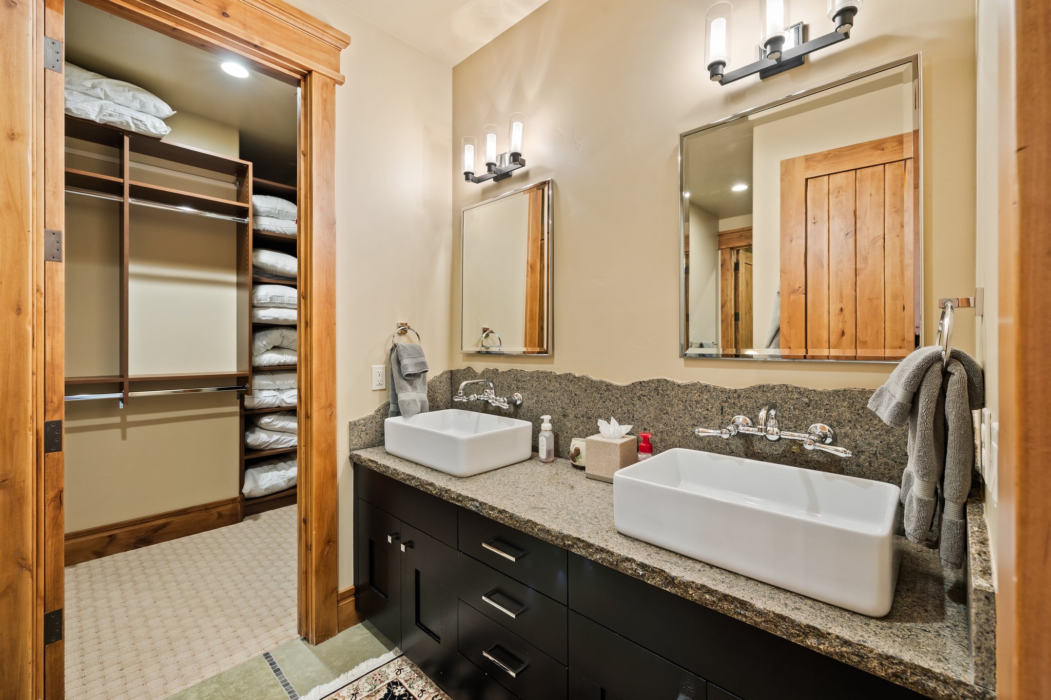 Dual vessel sinks with wall-mounted faucets and a textured stone backsplash