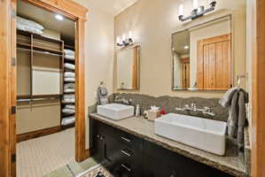 Dual vessel sinks with wall-mounted faucets and a textured stone backsplash