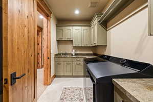 Utility area featuring wood-finish cabinetry, stone-look countertops, and a stainless steel sink