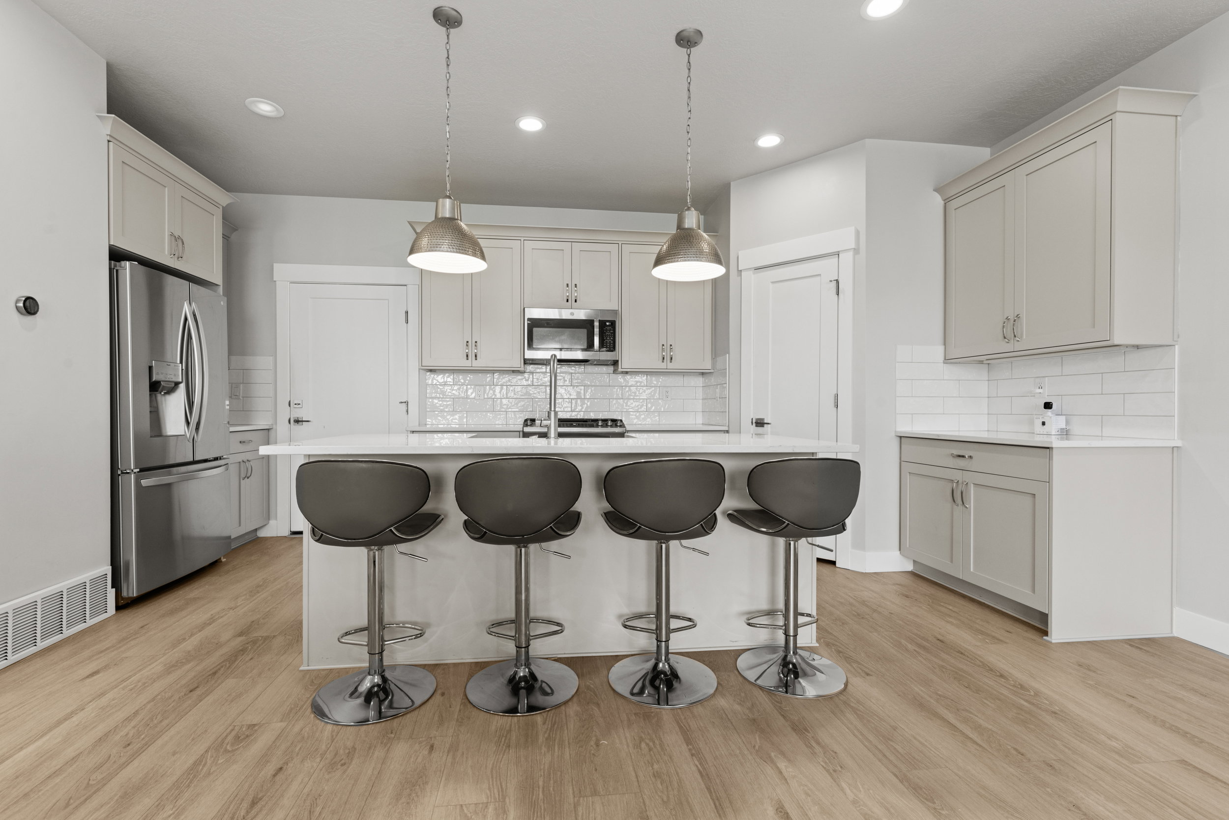 Kitchen featuring a central island with white countertop, pendant lighting, light wood-finish flooring, and light-toned cabinetry