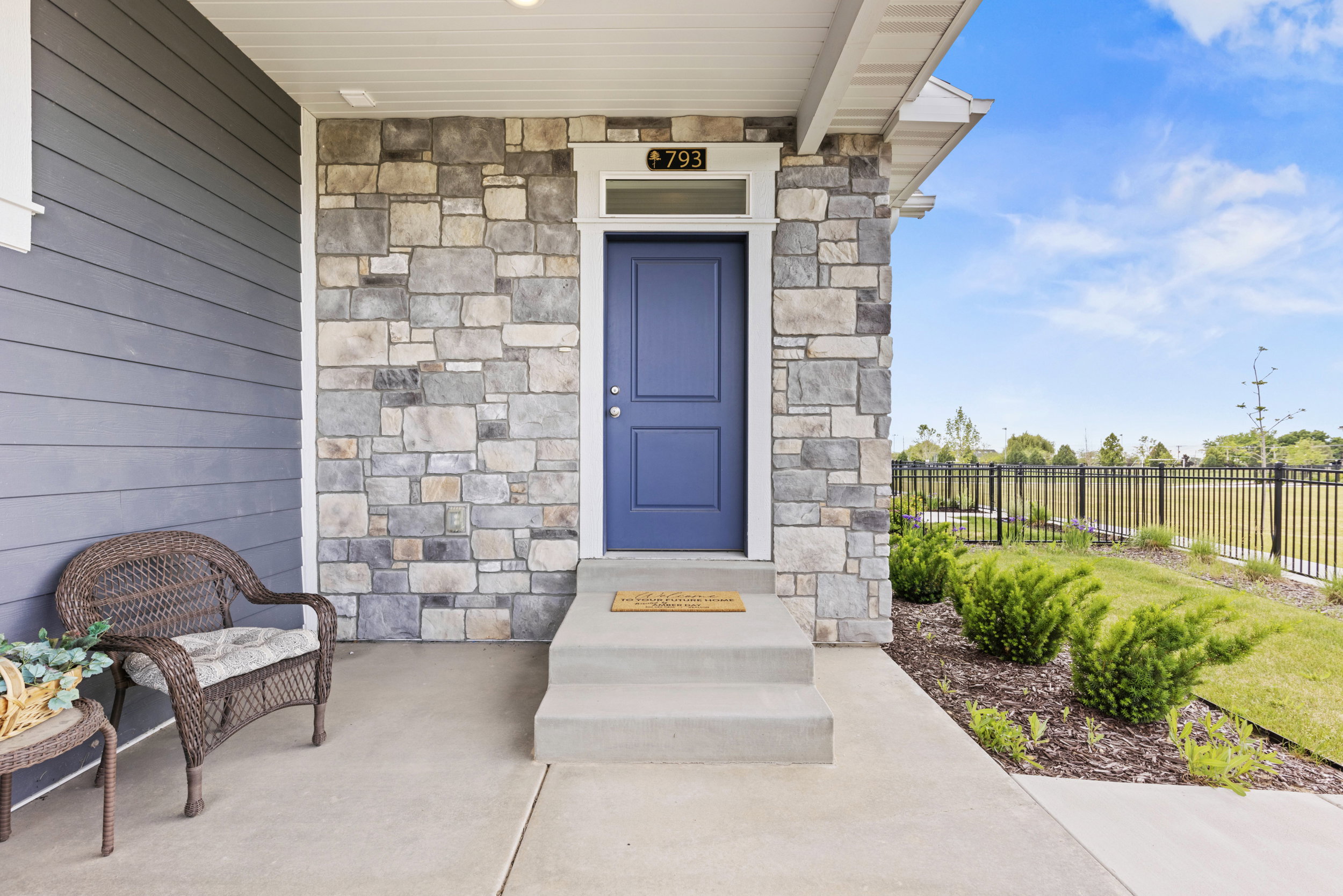 Entryway featuring a rich blue front door with transom window, stone facade accents, and horizontal siding