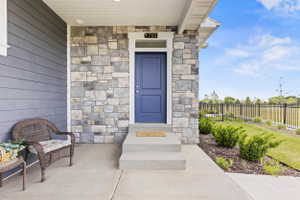 Entryway featuring a rich blue front door with transom window, stone facade accents, and horizontal siding