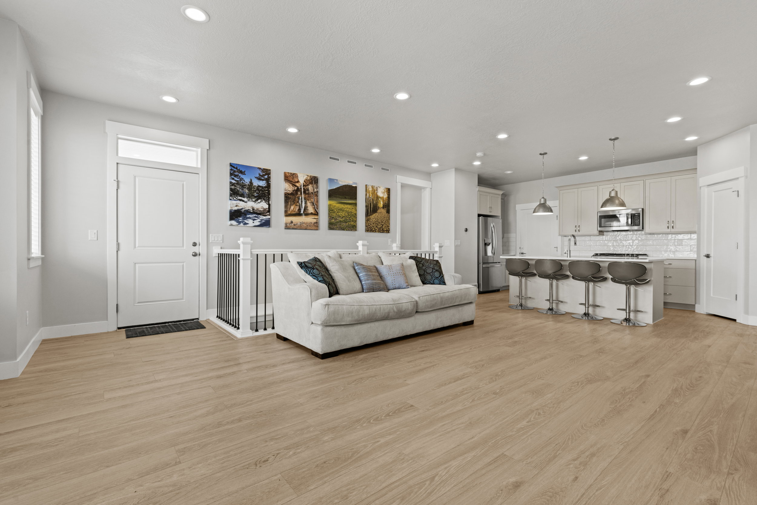 Open-concept living area featuring light wood-finish flooring, white cabinetry, and recessed lighting