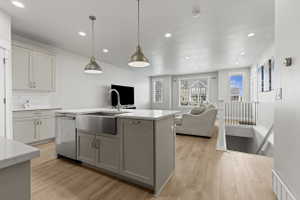 Kitchen island featuring a stainless steel farmhouse sink, integrated dishwasher, and pendant lighting