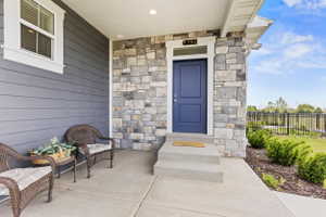 Covered entry featuring a blue paneled door with transom window, stone facade, gray horizontal siding, and concrete steps