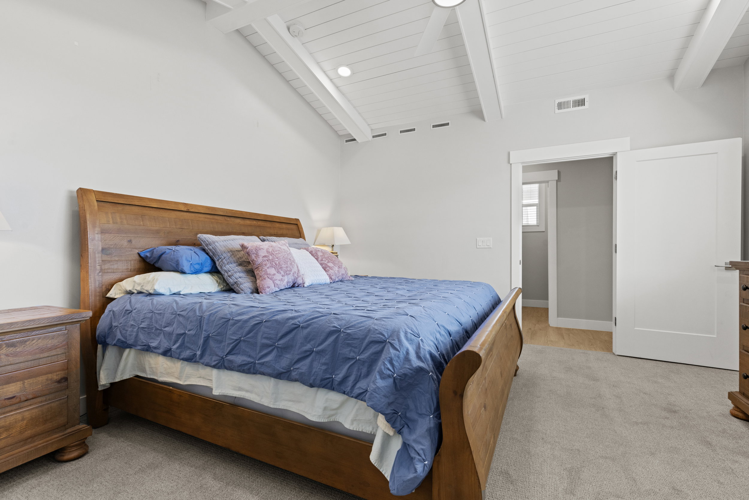 Vaulted white-paneled ceiling with exposed beams, recessed lighting, and a ceiling fan