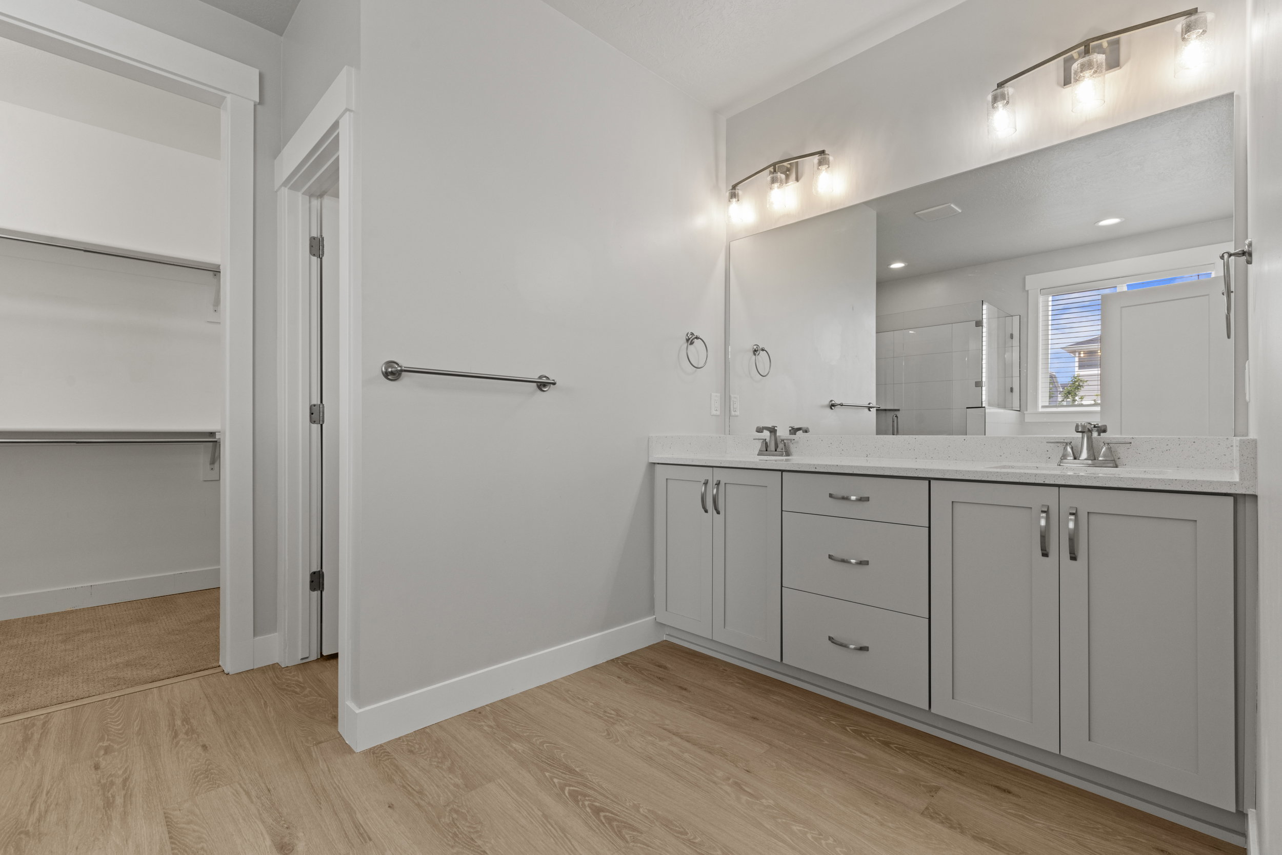 Bathroom featuring a dual vanity with light grey cabinetry, white countertops, and chrome fixtures