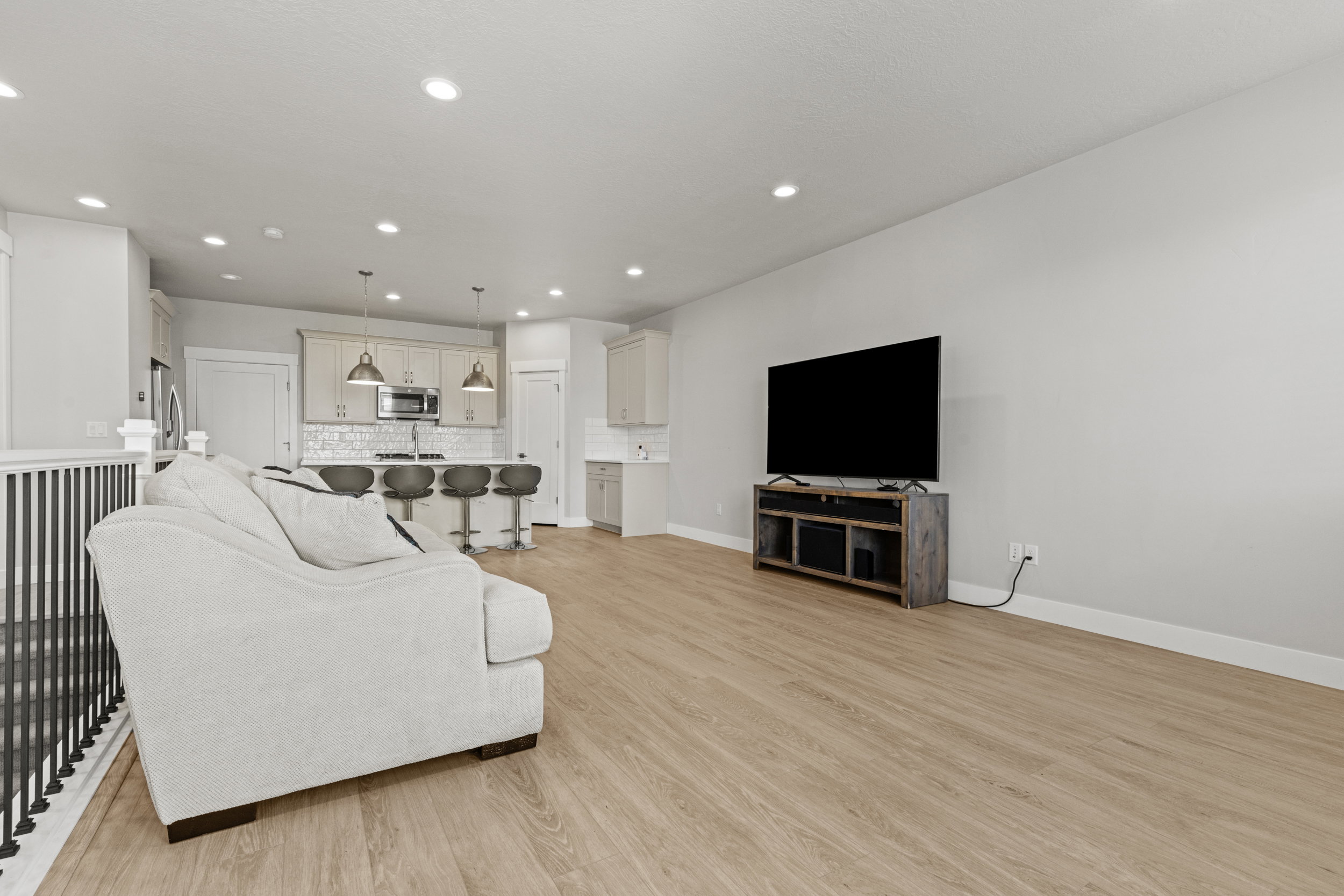 Open-concept living space featuring wood-finish flooring, recessed lighting, and a white balustrade