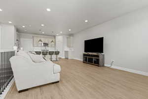 Open-concept living space featuring wood-finish flooring, recessed lighting, and a white balustrade