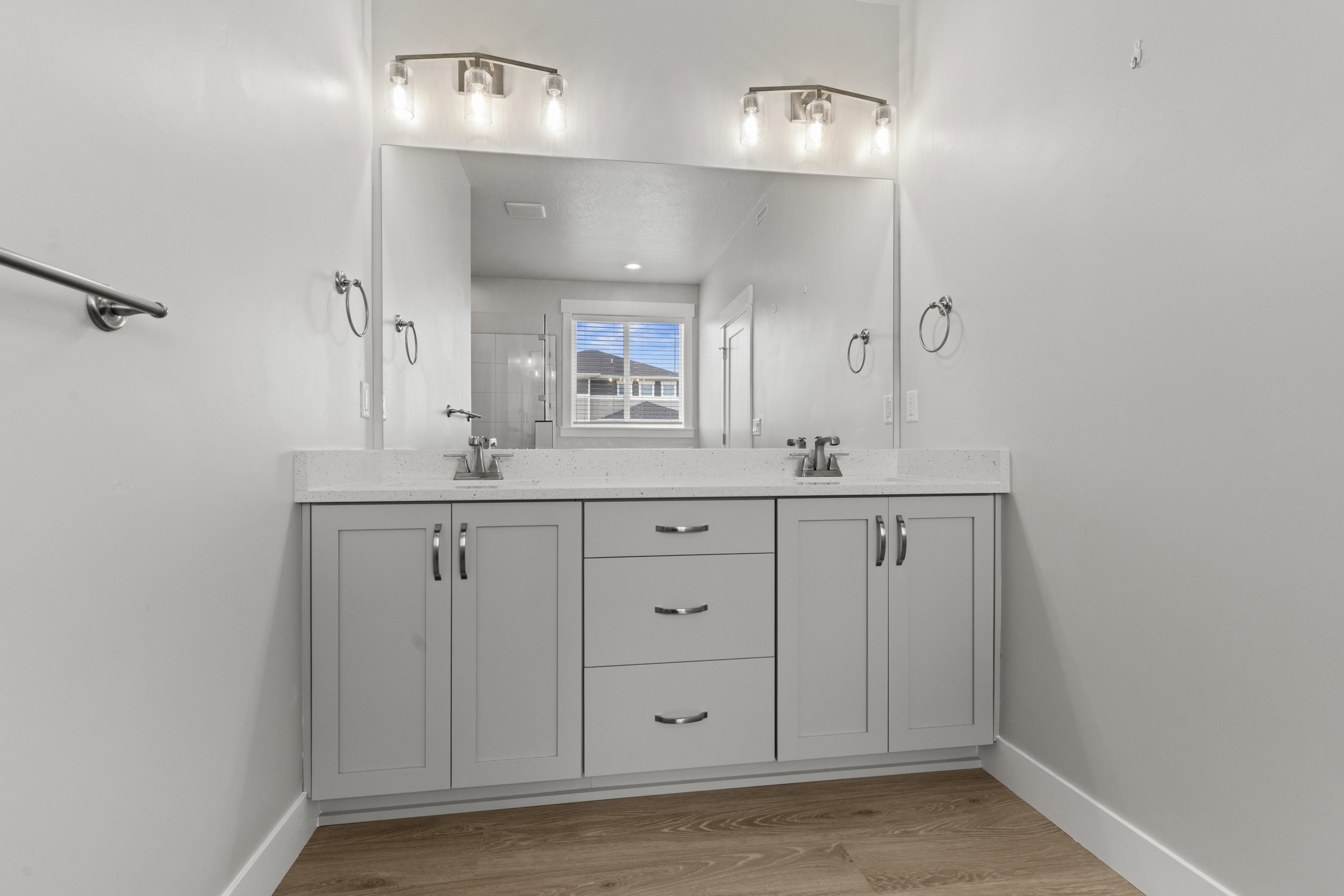 Dual vanity with light gray shaker cabinetry, chrome hardware, and a white countertop