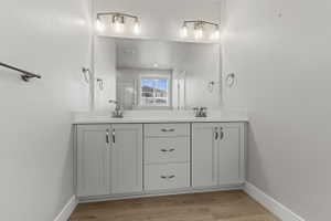Dual vanity with light gray shaker cabinetry, chrome hardware, and a white countertop