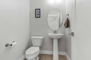 Pedestal sink with an oval mirror and brushed nickel fixtures