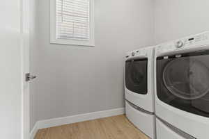 Dedicated laundry area featuring light wood-finish flooring, light gray wall paint, and white trim
