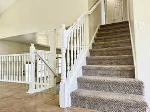 Carpeted staircase featuring white painted banisters and balusters