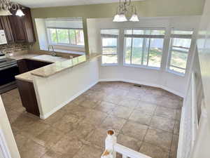 Kitchen and dining area featuring a breakfast bar with stone-finish countertops, dark wood-finish cabinetry, stainless steel appliances, and a tiled backsplash
