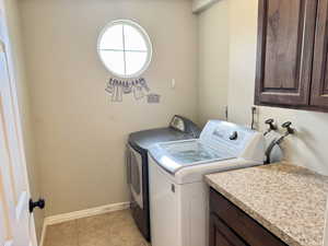 Dedicated utility space featuring a round window, tile flooring, and cabinetry with a light-toned countertop
